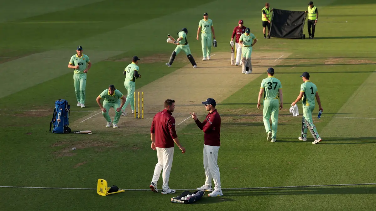 Medium view of fielders and a bowler set on a green cricket square during a tactical white-ball passage